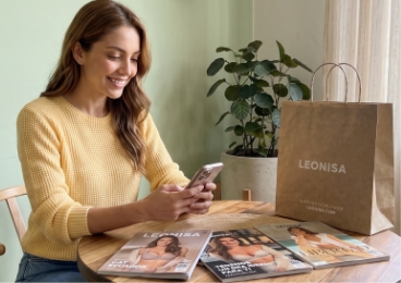 Mujer revisando su celular con catálogos Leonisa
